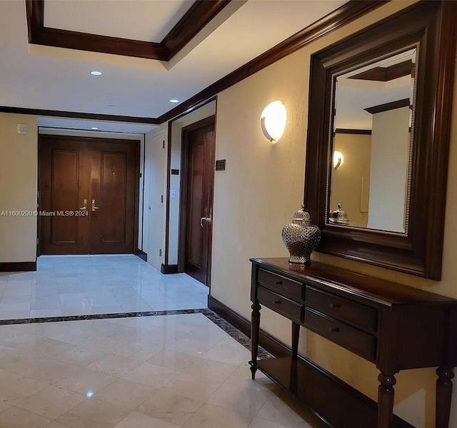 corridor with a tray ceiling, crown molding, and light tile patterned floors