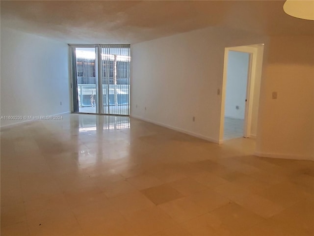 tiled empty room with a wall of windows and a healthy amount of sunlight