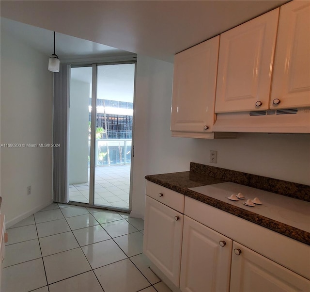 kitchen featuring white cabinets, dark stone countertops, premium range hood, and light tile patterned flooring