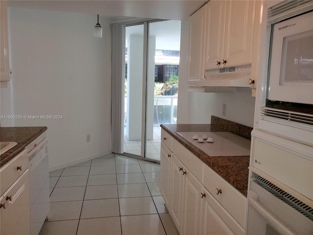 kitchen with oven, white cabinets, dishwasher, light tile patterned floors, and dark stone countertops