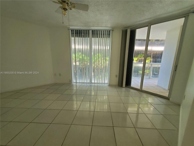 unfurnished room featuring light tile patterned flooring, ceiling fan, a textured ceiling, and floor to ceiling windows