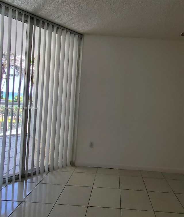 spare room featuring light tile patterned flooring, expansive windows, and a textured ceiling