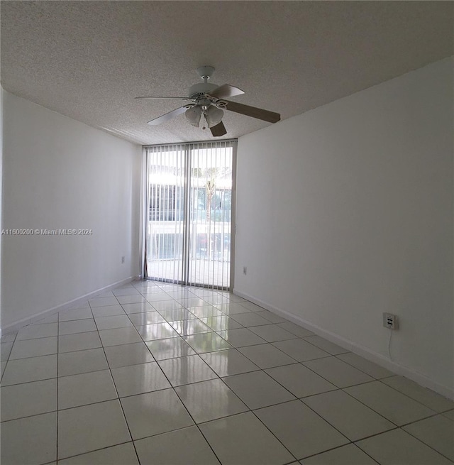 spare room featuring ceiling fan, a textured ceiling, light tile patterned flooring, and floor to ceiling windows