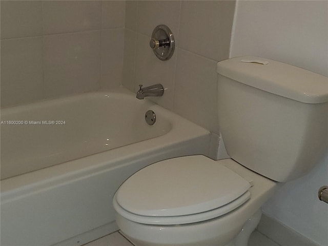 bathroom featuring tile patterned floors, tiled shower / bath combo, and toilet