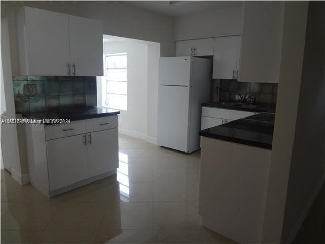 kitchen with backsplash, white fridge, white cabinetry, and light tile patterned flooring