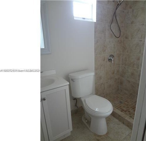 bathroom featuring tile patterned flooring, vanity, toilet, and a tile shower