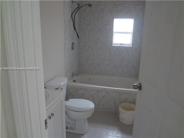 full bathroom featuring vanity, tiled shower / bath combo, and toilet