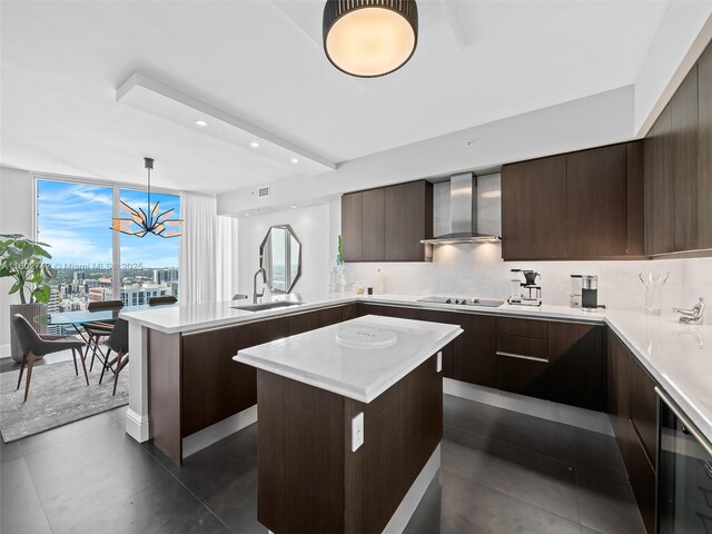 kitchen featuring pendant lighting, sink, a center island, wall chimney range hood, and black electric cooktop