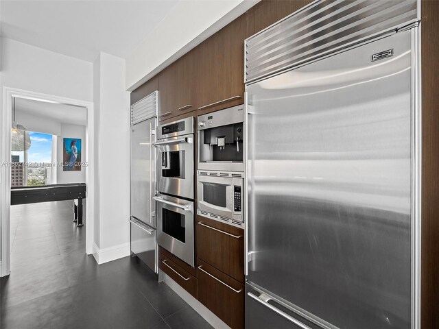 kitchen featuring built in appliances and dark brown cabinets