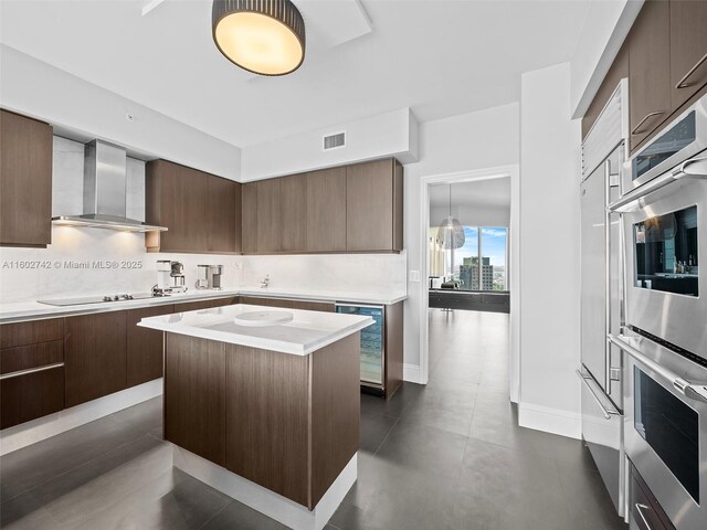 kitchen featuring a center island, wall chimney exhaust hood, wine cooler, black electric stovetop, and stainless steel double oven