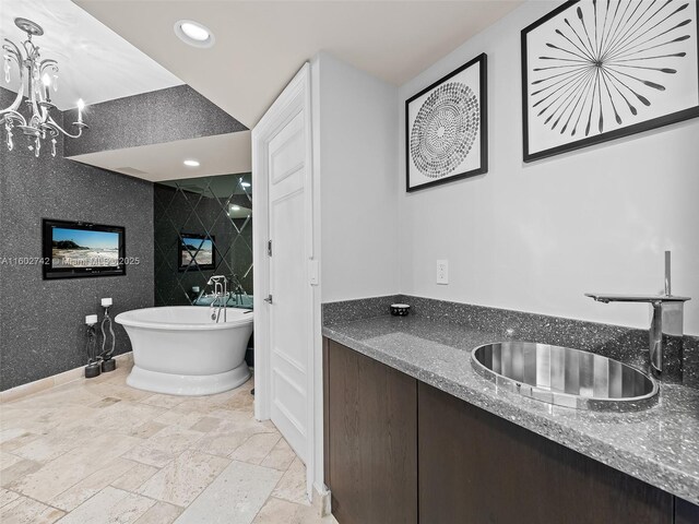 bathroom featuring sink, a chandelier, and a tub to relax in