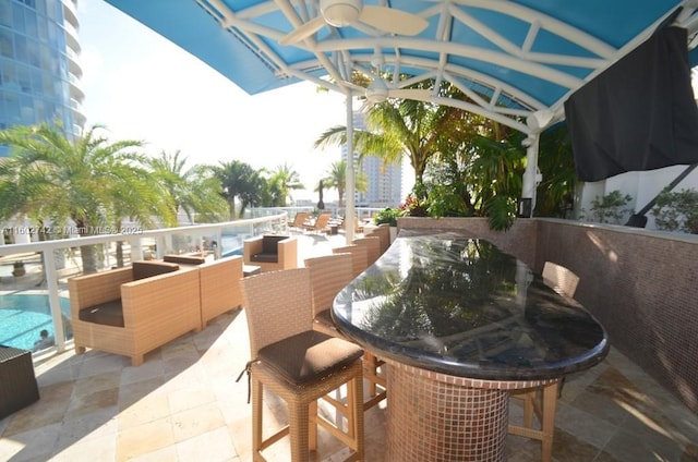 view of patio with ceiling fan and a bar