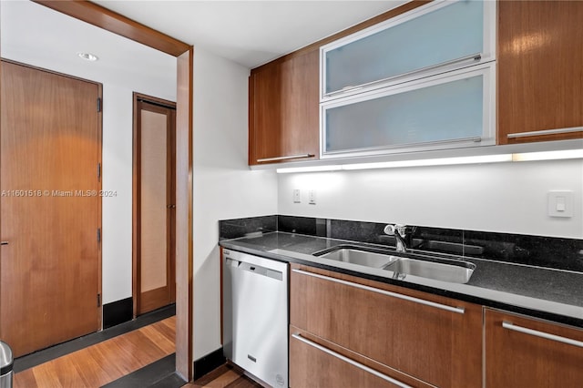 kitchen with dark stone counters, sink, dark wood-type flooring, and stainless steel dishwasher