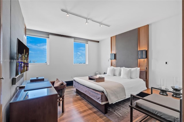 bedroom with light hardwood / wood-style floors and track lighting