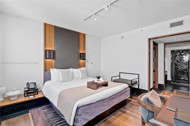 bedroom with hardwood / wood-style flooring and track lighting