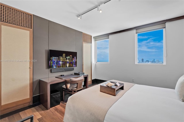 bedroom with rail lighting and light hardwood / wood-style flooring