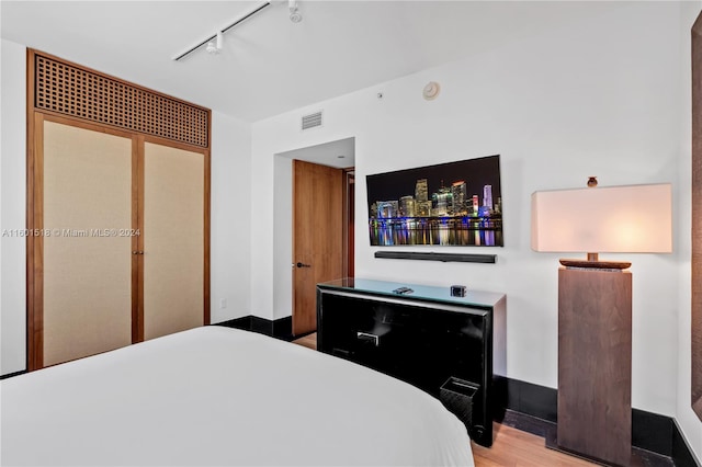 bedroom with a closet, rail lighting, and wood-type flooring