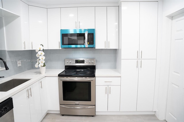 kitchen with backsplash, sink, stainless steel appliances, and white cabinets