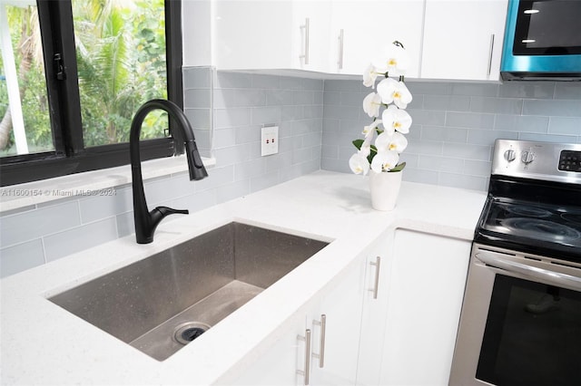 kitchen featuring decorative backsplash, stainless steel appliances, white cabinetry, and sink