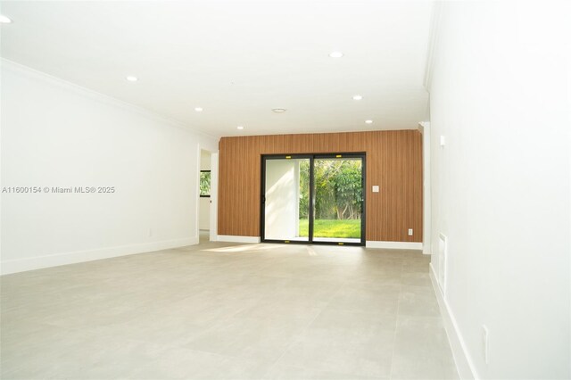 empty room with ornamental molding and wooden walls