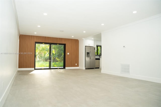 unfurnished room featuring wooden walls, crown molding, and sink