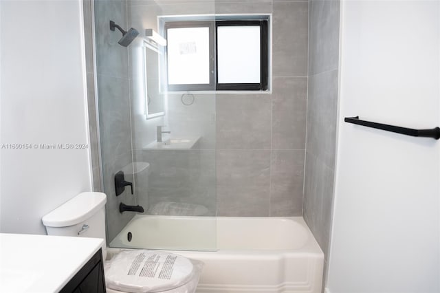 full bathroom with tiled shower / bath, vanity, and toilet