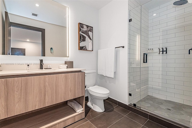 bathroom with tile patterned flooring, a shower with shower door, toilet, and vanity