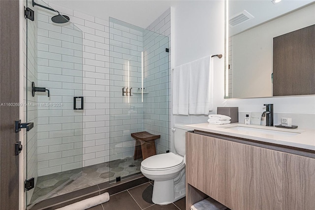 bathroom featuring vanity, a shower with door, tile patterned flooring, and toilet