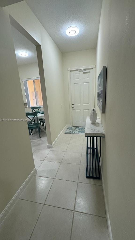 hall featuring light tile patterned floors and a textured ceiling