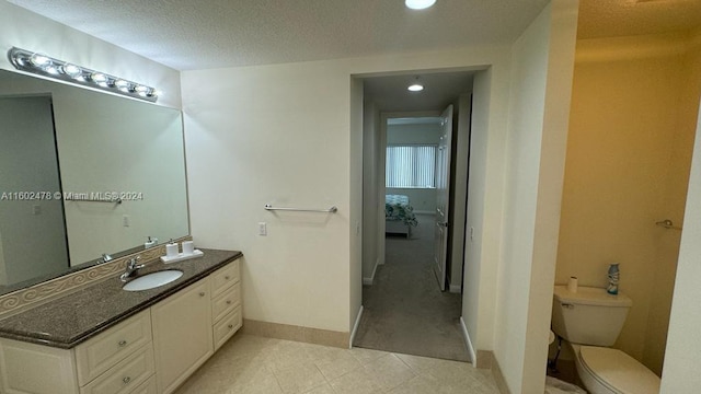 bathroom featuring a textured ceiling, vanity, toilet, and tile patterned flooring