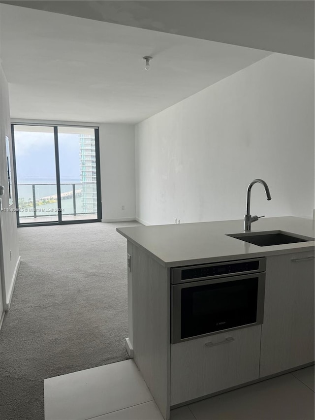 kitchen with oven, light carpet, kitchen peninsula, and sink