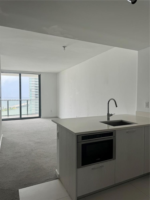 kitchen featuring oven, sink, light carpet, and kitchen peninsula