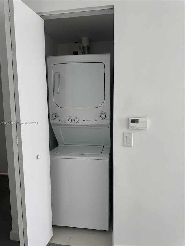 laundry area with light tile patterned flooring and stacked washer / drying machine