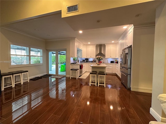 kitchen featuring ornamental molding, white cabinets, dark hardwood / wood-style floors, double oven, and wall chimney exhaust hood