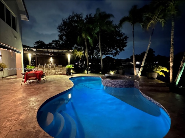 pool at night featuring a patio, an in ground hot tub, and a pergola