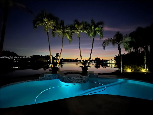 pool at dusk featuring an in ground hot tub