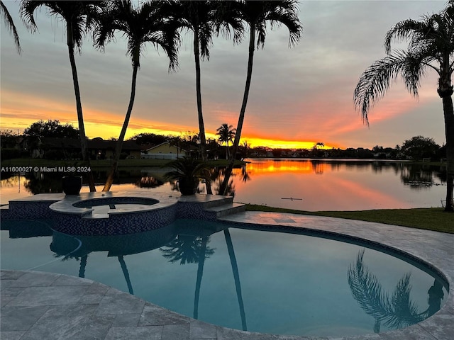 pool at dusk featuring an in ground hot tub