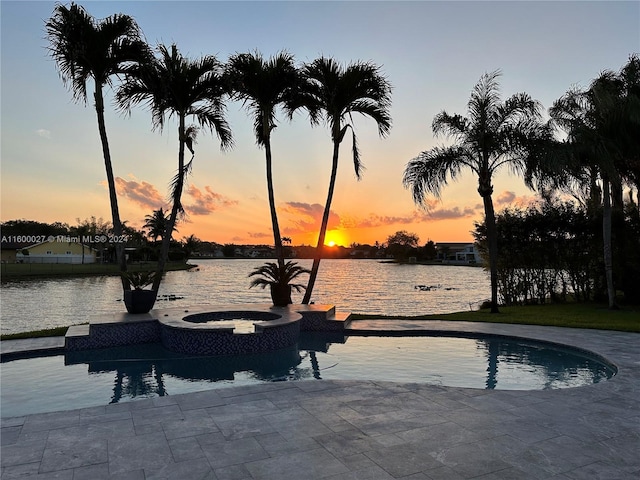 pool at dusk with an in ground hot tub