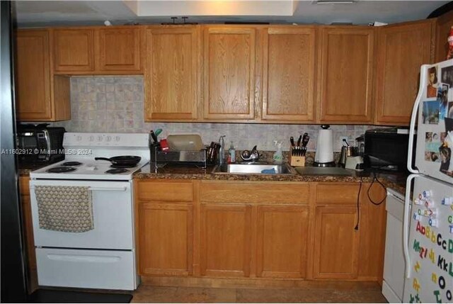 kitchen with decorative backsplash, sink, dark stone counters, and white appliances