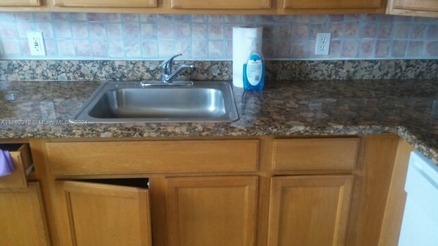 kitchen featuring decorative backsplash, dark stone counters, and sink