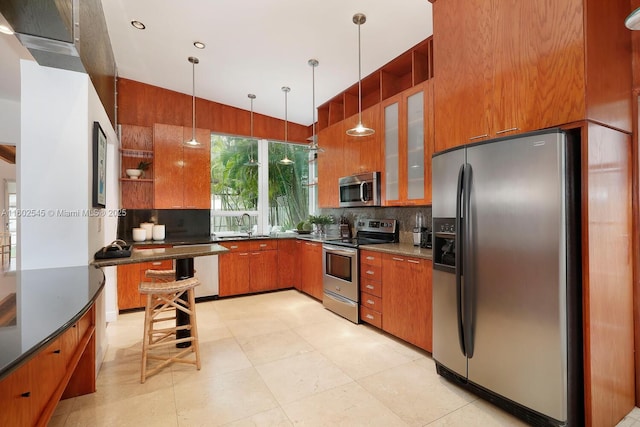 kitchen featuring tasteful backsplash, stainless steel appliances, a sink, dark countertops, and brown cabinets