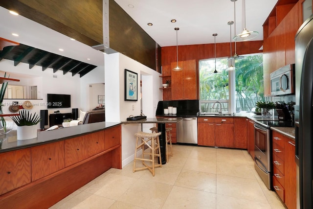 kitchen with a sink, open shelves, appliances with stainless steel finishes, brown cabinets, and dark countertops