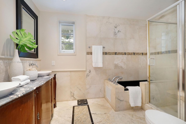 bathroom with tile walls, double vanity, a sink, and a stall shower