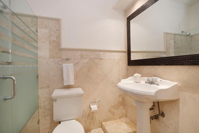 full bath featuring toilet, a stall shower, and tile walls