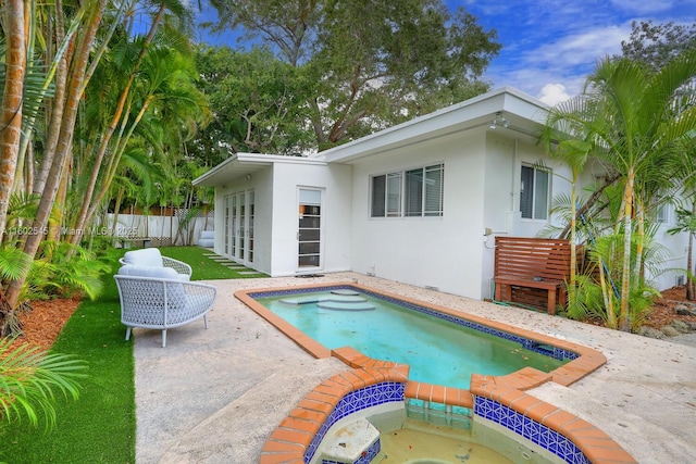 view of swimming pool featuring fence, an in ground hot tub, and a patio area