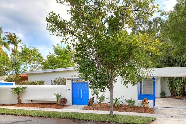 view of front of home with an attached carport, stucco siding, and fence