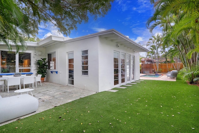 rear view of house featuring a lawn, a patio area, and a fenced in pool