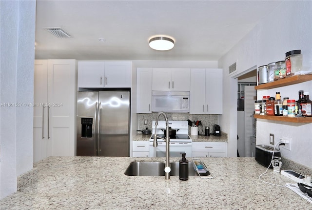 kitchen featuring light stone counters, white appliances, tasteful backsplash, and white cabinets