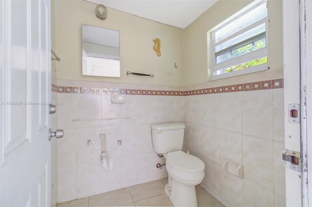 bathroom featuring tile patterned flooring, a wainscoted wall, toilet, and tile walls