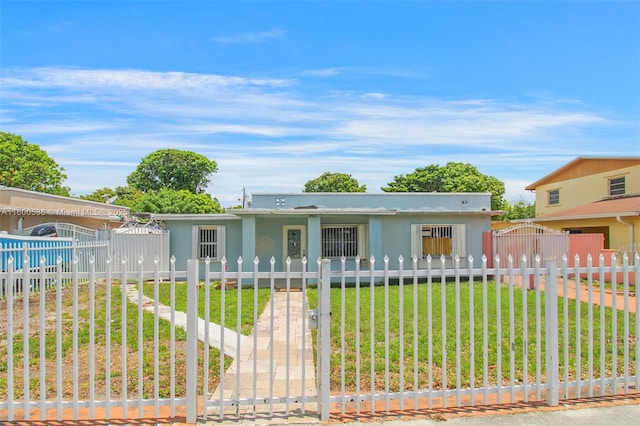 view of front facade with a fenced front yard, stucco siding, a front yard, and a gate